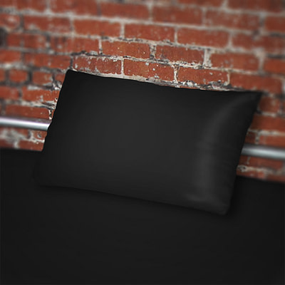 Fluidproof Black pillowcase on bed against a brick wall